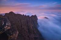  After an all-nighter on the Summit of Cradle Mountain I was privileged enough to witness a dawn like no other I had seen. It was a photographers heaven and I knew that it would be many climbs to come before I witnessed something like this again. This was a moment from my dreams.

But there was a problem... I was so overwhelmed by it all that I couldn't seem to steady myself long enough to take a decent photo. Knowing this may well be the only time I ever see a dawn like this from such an amazing place seemed to flood panic into my mind. It got worse with the threat of the moment going past and none of its glory being captured.

But amongst the adrenalin and rush of blood something stood me still and told me to breathe. I turned my back on it all and just tried to still my mind. Then something in my head said 'what stands out' and in this case it was the cloud around little horn. So after a little time spent calming myself and a little bit of climbing I found a place for my tripod at the edge of the mountain and set off a 30 second exposure. Then it came up on the screen on the back of my camera...

I don't think I took another shot for 30mins or so (after shooting non stop since 3pm the day before) I just sat there and enjoyed the moment.

I had taken an image that truly represented how I felt about what I was experiencing.

I feel as if the work of the great Peter Dombrovskis guides many photographers and certainly has me. He influences what we do and somehow he lives on through it all. He is gone but maybe what motivated Peter is still alive. Maybe in our quest for good light and exploration we all share a little bit of the Spirit of Dombrovskis.

I recently drove to Hobart to meet with Liz Dombrovskis the wife of Peter to ask her face to face for her permission/blessing for the use of the Family name in this image. She was happy for me to use it and was also happy to share a few wonderful stories about Peter. What an amazing man.